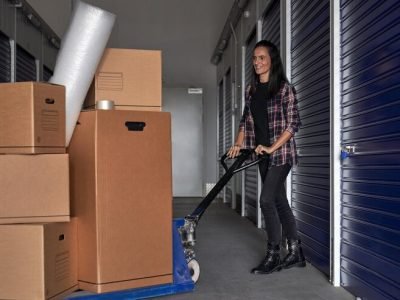 full-body-positive-female-using-special-pallet-jack-roll-pile-carton-boxes-near-self-storage-moving-day_935394-4156